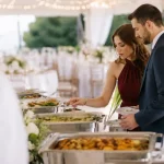 Couple choosing dishes from a wedding catering